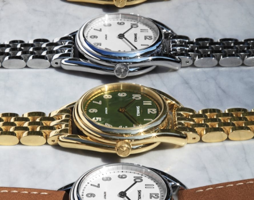 An image of four Derby watches in different colors and styles next to a model smiling wearing the Derby watch