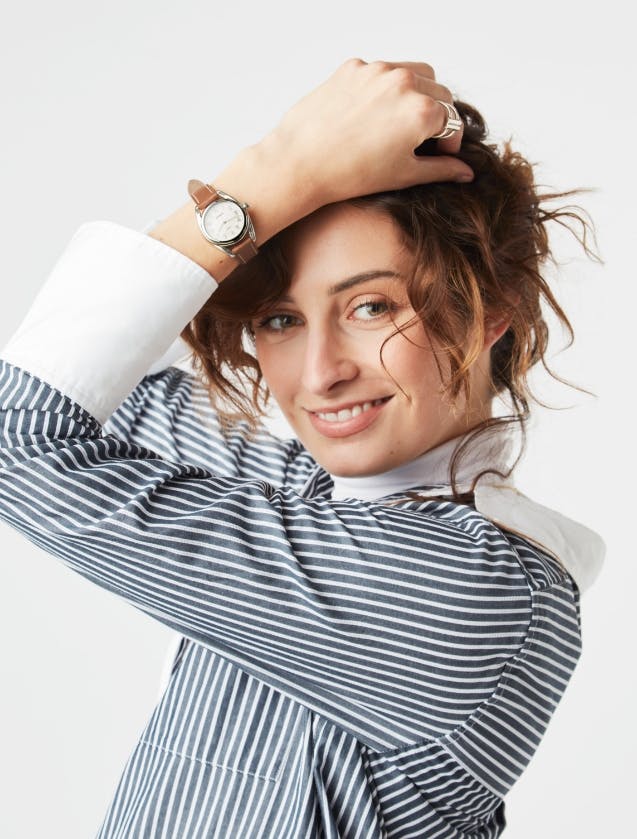 An image of four Derby watches in different colors and styles next to a model smiling wearing the Derby watch
