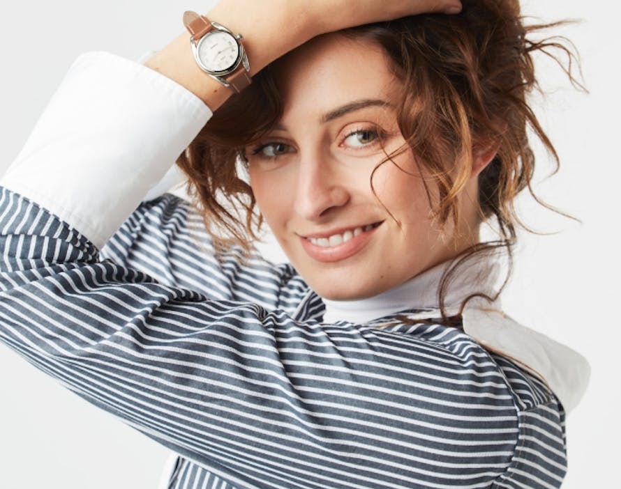An image of four Derby watches in different colors and styles next to a model smiling wearing the Derby watch