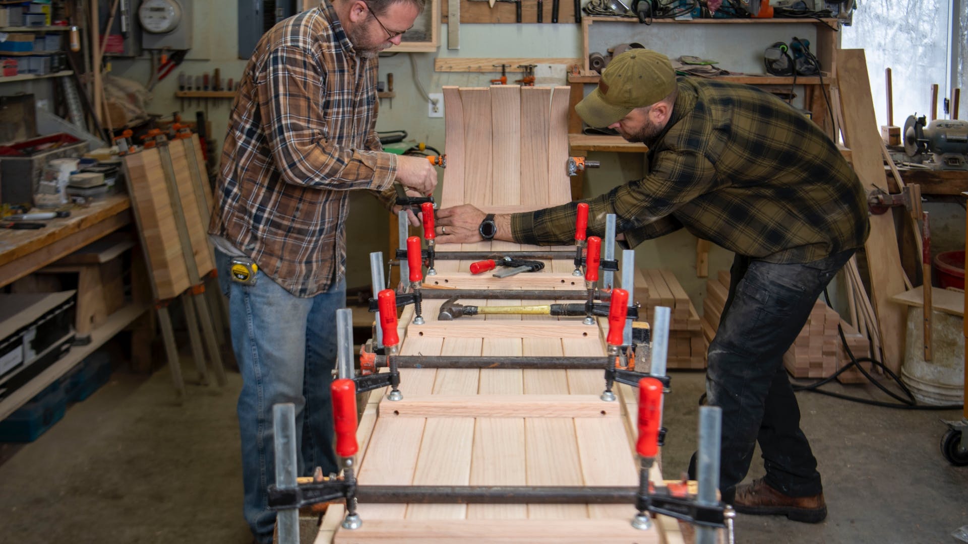 Two men in the Northern Toboggan workshop bend the wood to create a signature curved front.