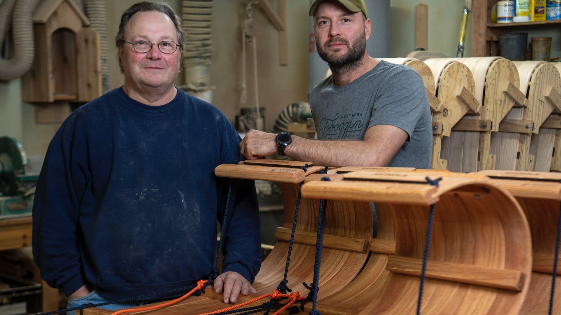 Father and son John and Jackson Harren pose with completed toboggans at their workshop in Minnesota.